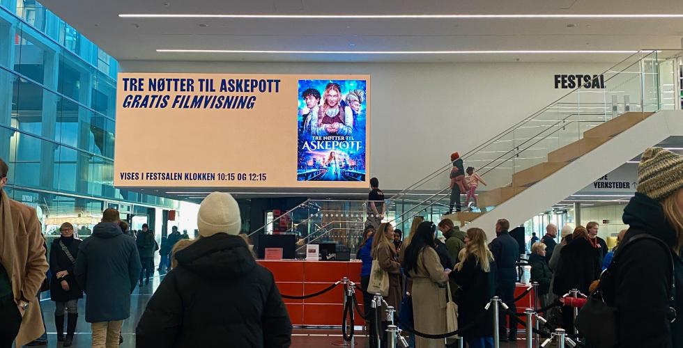 Det er k&oslash; i lobbyen p&aring; Munchmuseet. I bakgrunnen ser man en stor plakat med informasjon om jule&aring;pningen
