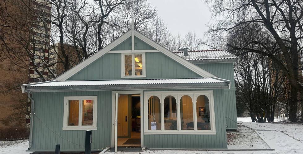 Det restaurerte Nabolagshuset fra forsiden, &aring;pen d&oslash;r, lys i vinduene