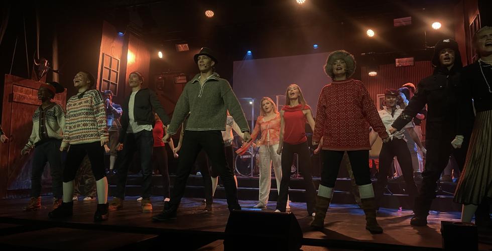 En scene med videreg&aring;ende elever i kostymer som synger og danser