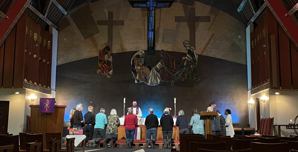 En gjeng mennesker kneler ved alteret