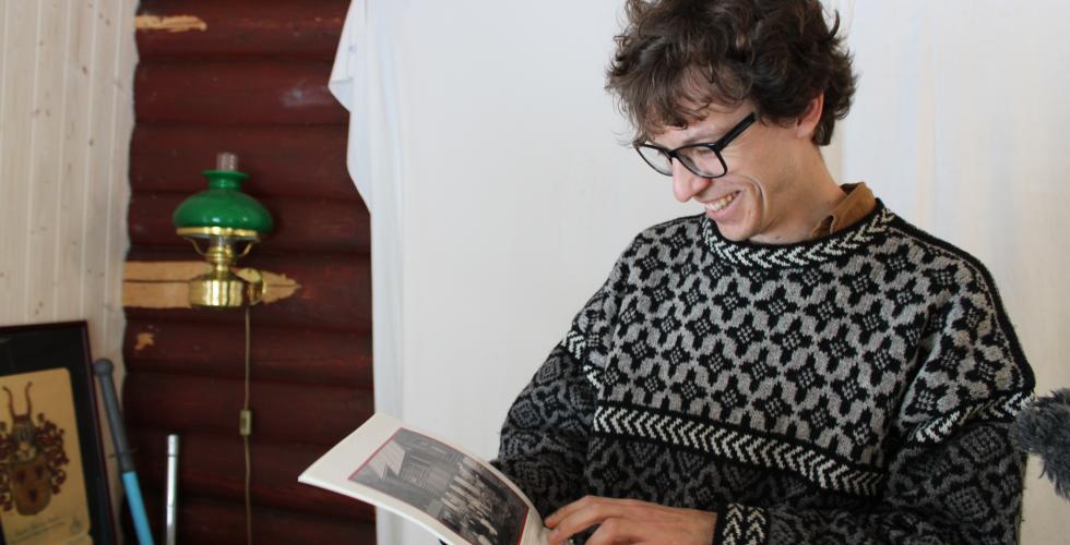 mann smiler og ser p&aring; bok