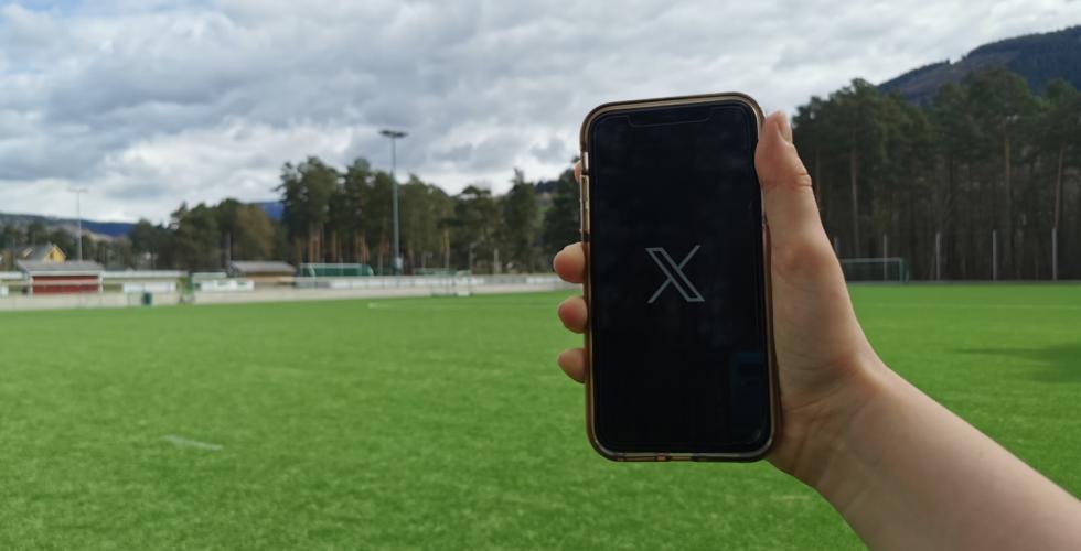 Telefon med X-logo ved fotballbane