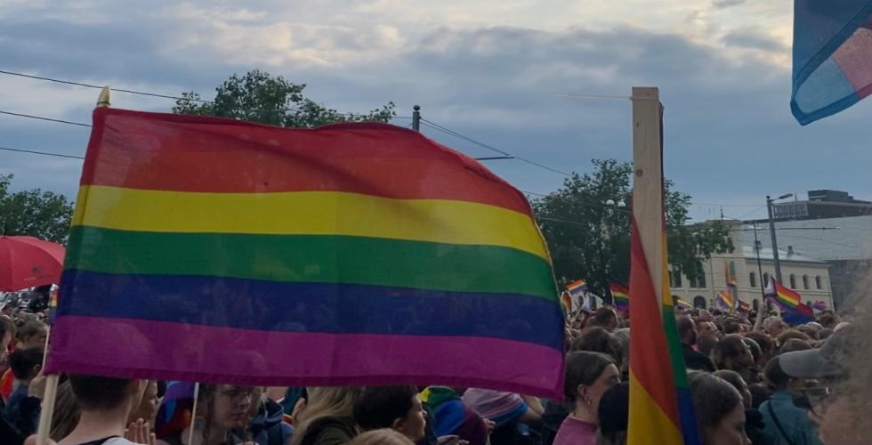 Prideflagg i forgrunnen og mange mennesker i bakgrunnen