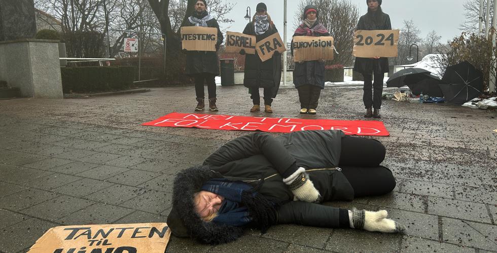 Demonstrant ligger p&aring; bakken med et skilt som sier "Tanten til Hind". I bakgrunnen ser man flere demonstranter som holder skilt med budskapet om at Israel m&aring; boikottes fra Eurovision.