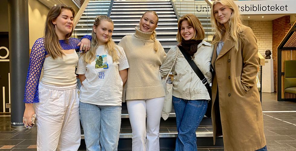 5 jenter st&aring;r foran ei trapp. De smiler.