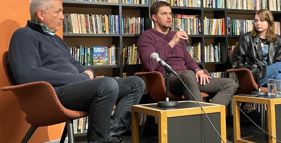 Tre mennesker sittende p&aring; en scene