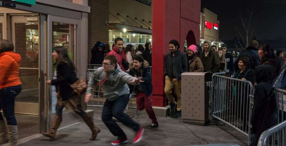 mann l&oslash;per inn i en butikk p&aring; black friday fordi det er store salg. 