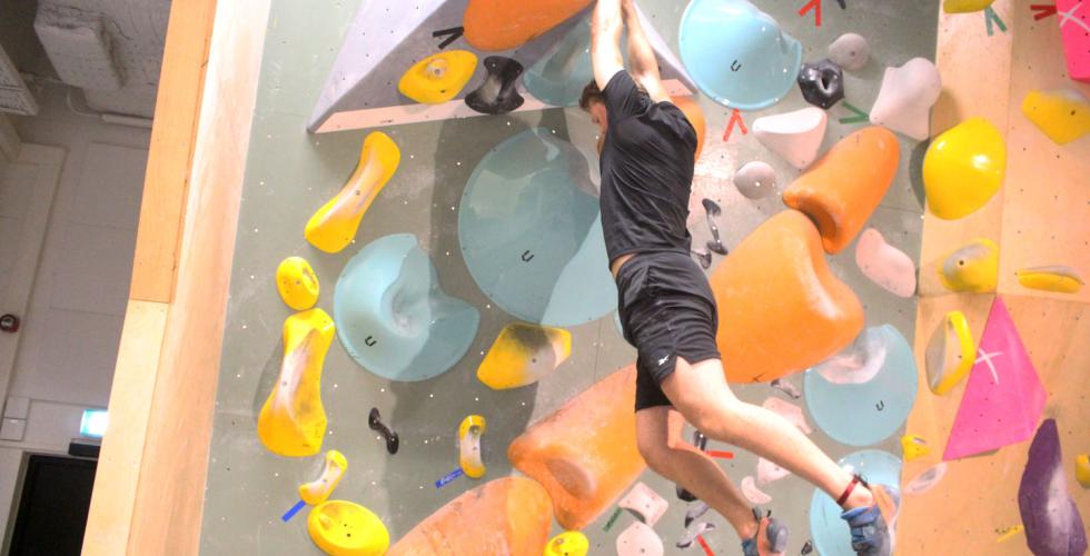 Bilde av en gutt som buldrer p&aring; en fargerik vegg