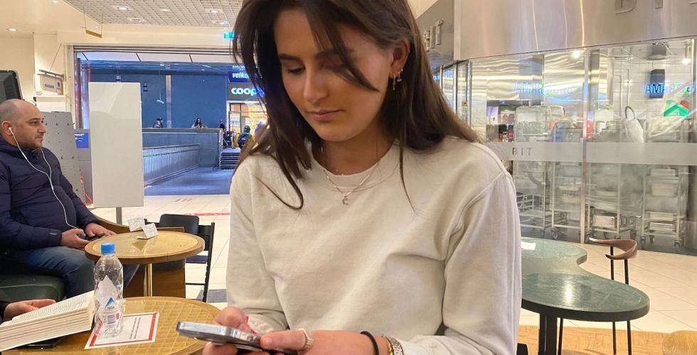 En jente med tlf p&aring; kaf&eacute;