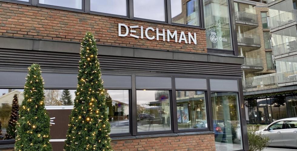 P&aring; utsiden av Deichman R&oslash;a. To tr&aelig;r med lys foran bygningen.