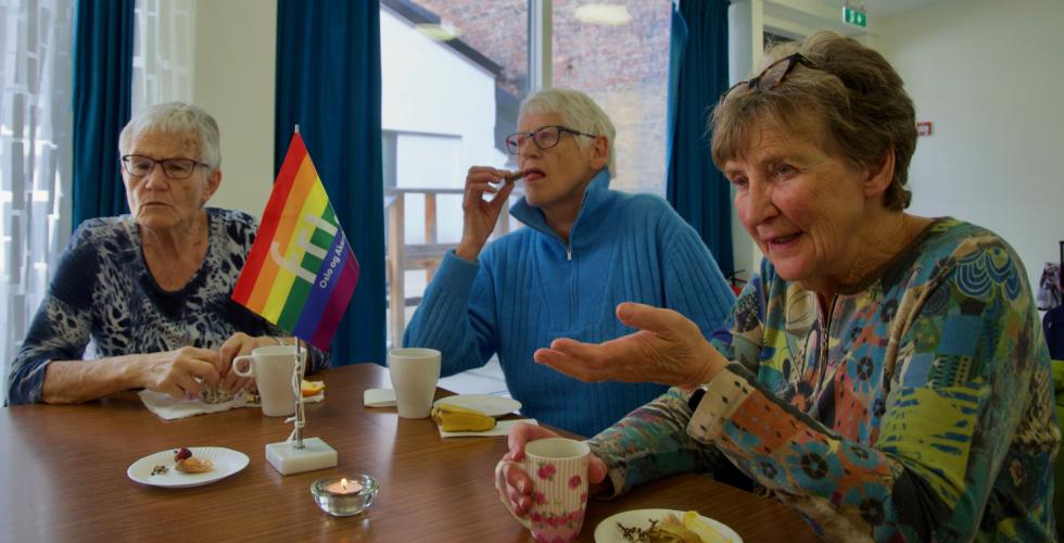 Damer som sitter rundt et bord p&aring; Regnbuetreff for senior