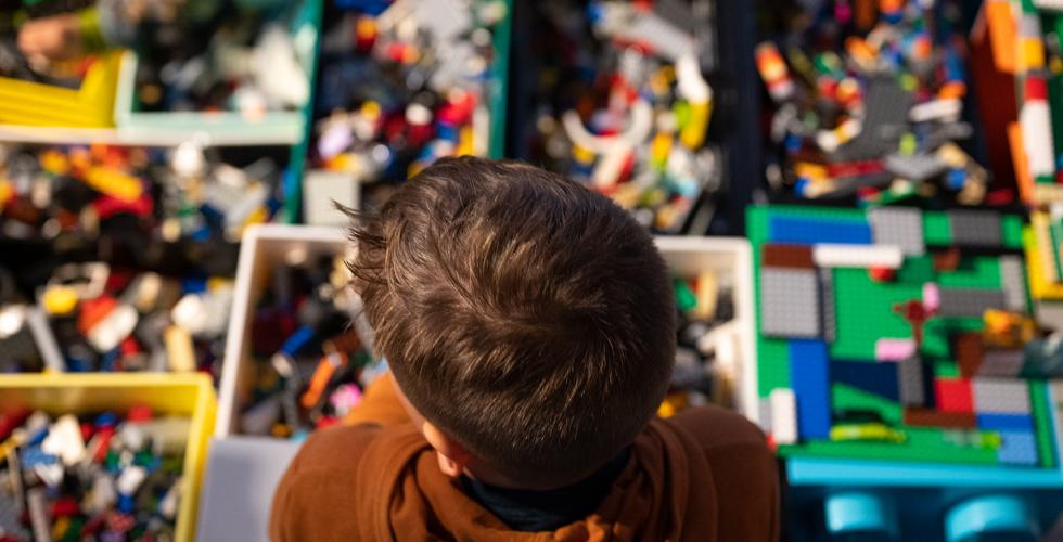 Bildet viser bakhodet til en gutt fra en h&oslash;y vinkel, som ser utover et legobord.