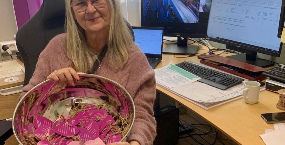 Eldre dame holder et s&oslash;lvfat med lilla hjerter oppi