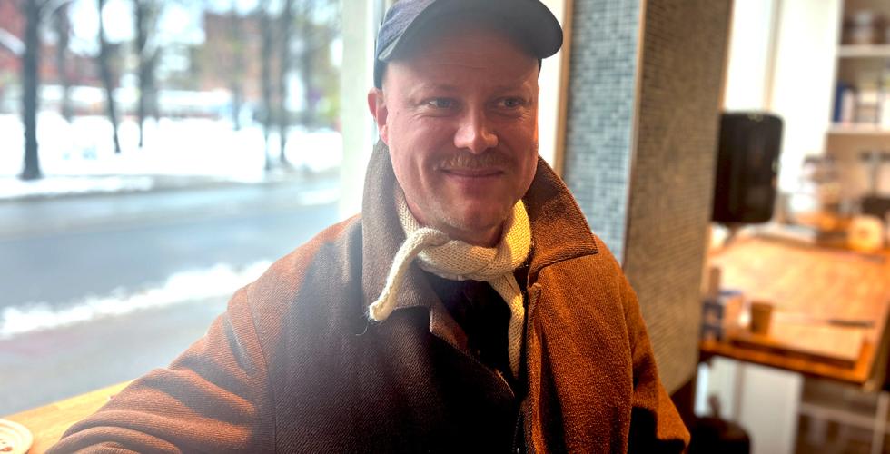 Bildet portretterer en mann, han er leder av bakeriet Mj&oslash;l. Han sitter foran et vindu 