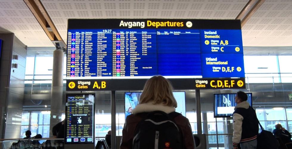 En jente st&aring;r foran en skjerm p&aring; Gardemoen og ser p&aring; gatetidene