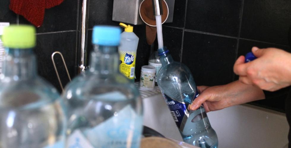 Vannflaske som fylles p&aring; i en vask p&aring; et kj&oslash;kken.