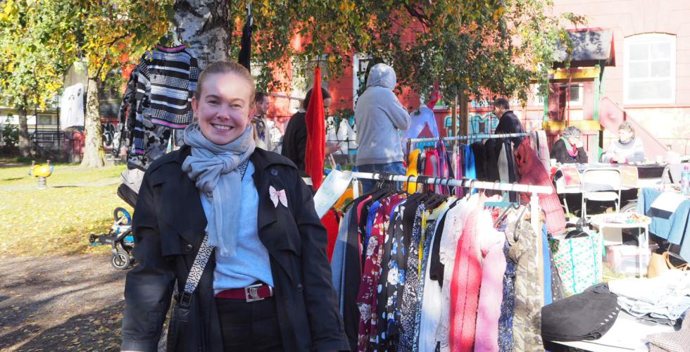 Dame st&aring;r foran et stativ med kl&aelig;r p&aring; et loppemarked