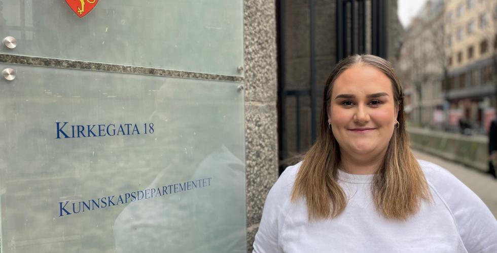 Kvinne st&aring;r foran Kunnskapsdepartementet