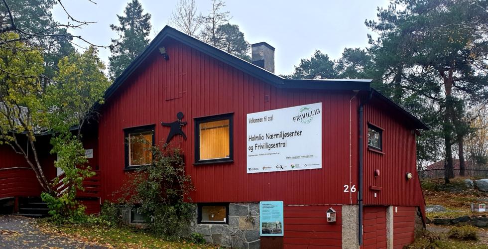 R&oslash;dt trebygg med et stort hvitt skilt der det st&aring;r  Holmlia N&aelig;rmilj&oslash; og Frivilligsentral