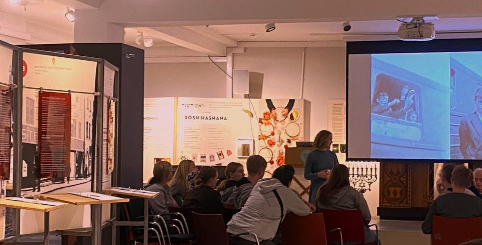 forsamling som h&oslash;rer p&aring; et tidsvitne fortelle om holocaust