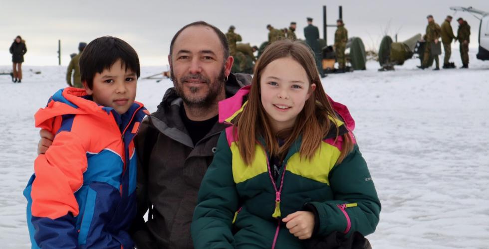 En far med sin s&oslash;nn og datter med kanoner og uniformerte menn i bakgrunn