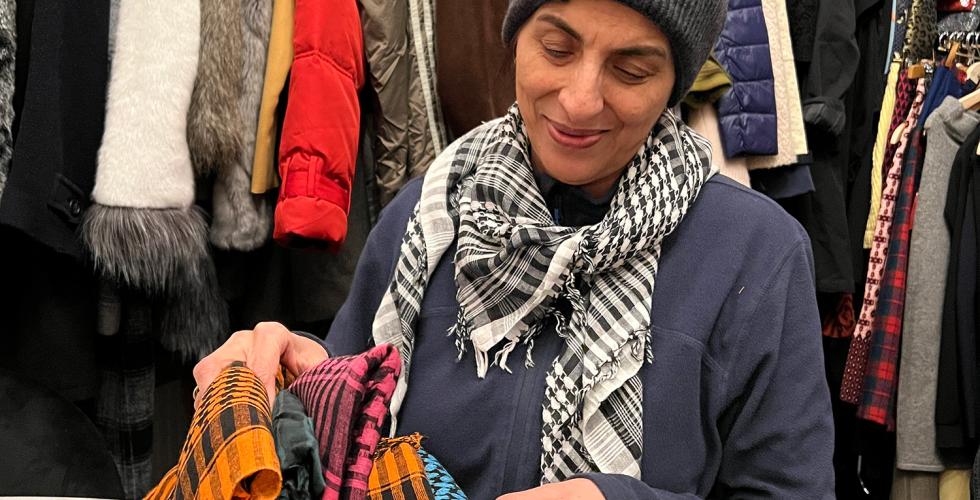 dame foran vegg av kl&aelig;r, ser igjennom skjerf