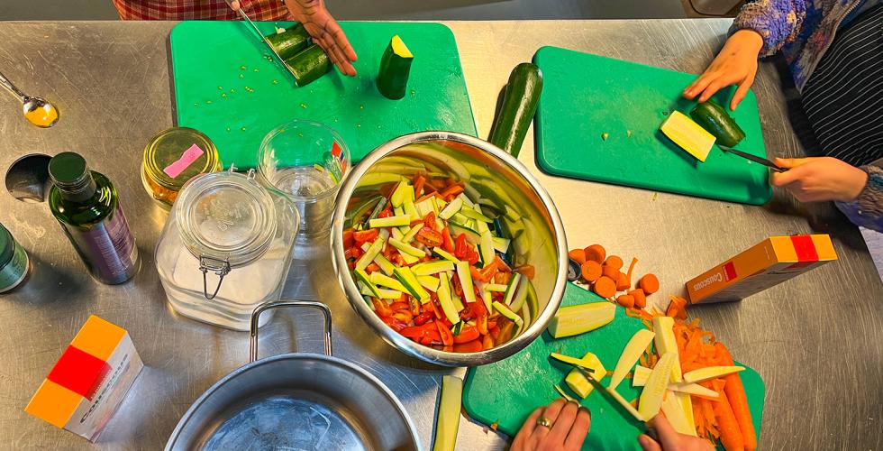 To barn st&aring;r ved kj&oslash;kkenbenket og skj&aelig;rer gr&oslash;nnsaker sammen med en voksen, FotO: Kiana Hassani