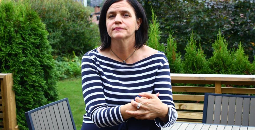 Tove Bj&oslash;rgaas sitter p&aring; et bord p&aring; terrassen med hagen i bakgrunnen