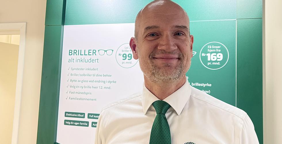 Portrett av optiker Carsten foran gr&oslash;nn vegg p&aring; Brilleland