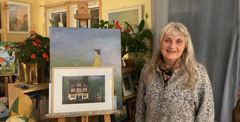 Gerd Eva Baum-Thoresen st&aring;r foran sitt egetmalt maleri av Kobro-huset.