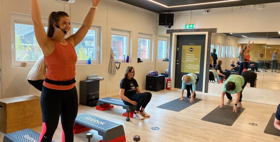 Ida Cecilie Juhasz som er instrukt&oslash;r for seniorer p&aring; Lia treningssenter smiler med armene i v&aelig;ret under gruppetimen