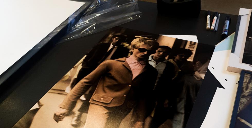 Man ser et bord, med bilderammer og bilder p&aring;, med teip og tusjer str&oslash;dd rundt p&aring; bordet. 