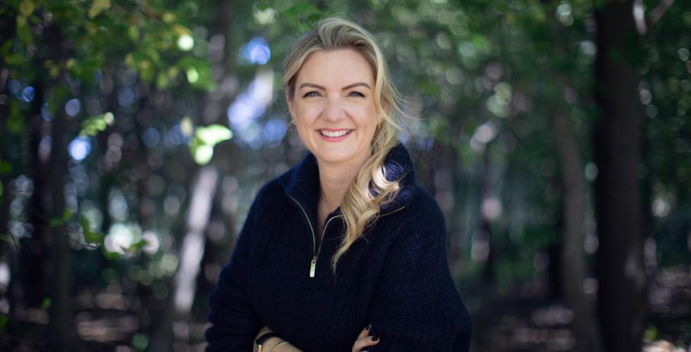 dame med blondt h&aring;r smiler mot kamera 