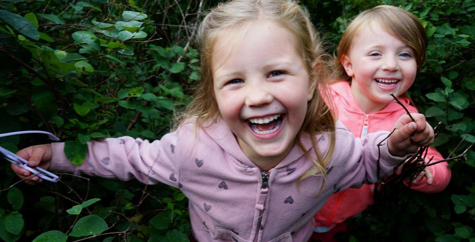 To jenter leker gjemsel i gr&oslash;nne busker