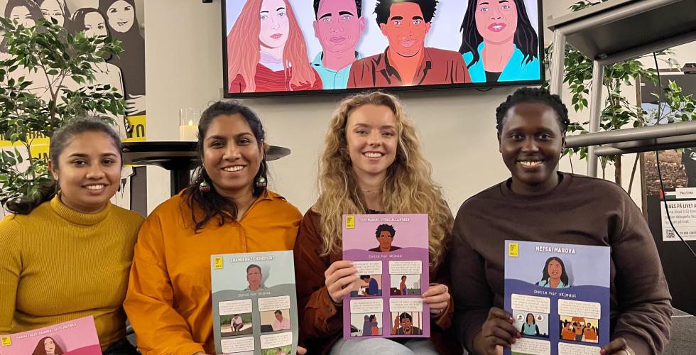 Fire unge kvinner sitter p&aring; en scene og viser frem plakater