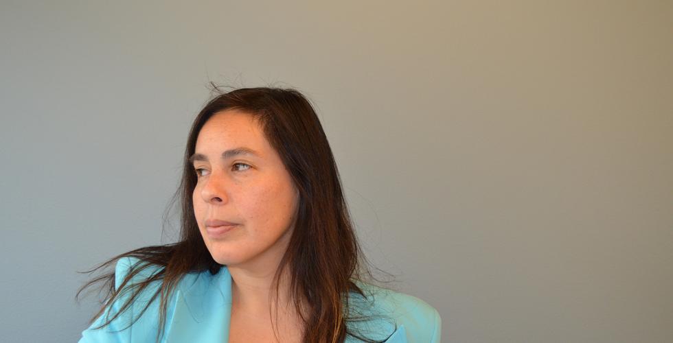 En kvinne fra Chile st&aring;r i bl&aring; jakke og ser alvorlig utover