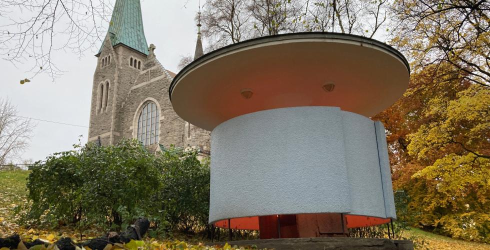 Kj&aelig;rlighetskarusellen st&aring;r nedenfor en kirke i Stensparken, til h&oslash;yre i bildet. Det lyser fra bygget.  
