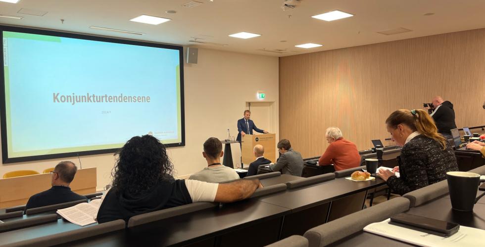 En sal med noen mennesker, projektor og en p&aring; talerstolen