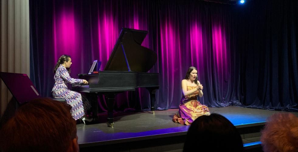 Operasanger sitter p&aring; scenen og pianist spiller piano