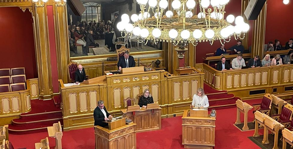 P&aring; bildet ser man en stor sal, med gullmalt interi&oslash;r, og r&oslash;de tepper kler gulvet. Vi ser et stort kunstverk, en stor lysekrone. Vi ser 16 mennesker p&aring; bildet. En kvinne har p&aring; seg hvite kl&aelig;r.