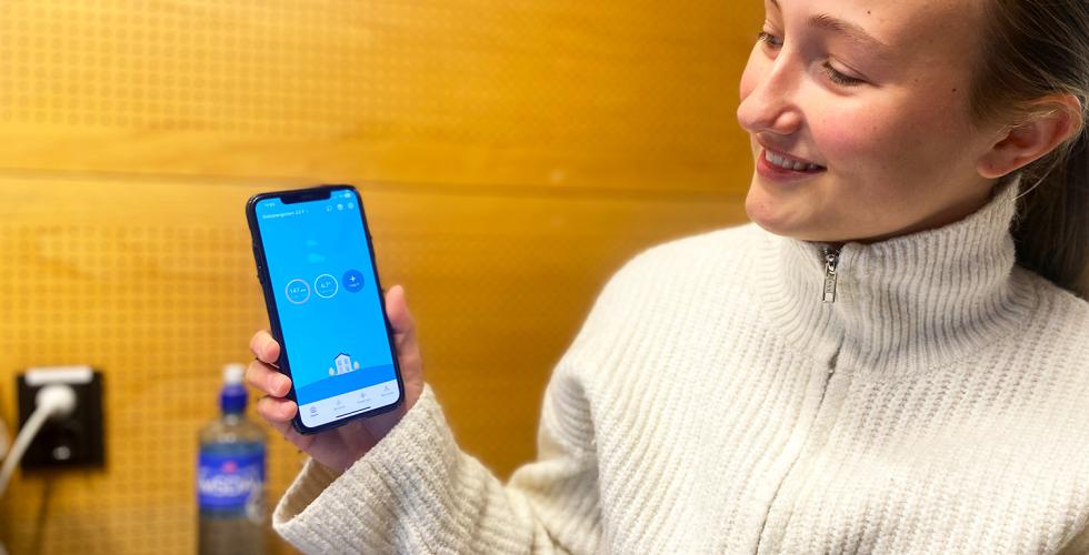 Student viser frem telefon med str&oslash;mapp