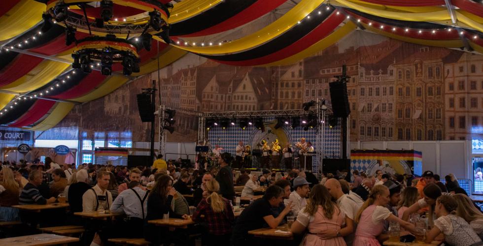 Inn i teltet til oktoberfest. Vi ser flere personer som har det g&oslash;y og h&oslash;rer p&aring; de tyske sangene i bakgrunnen.