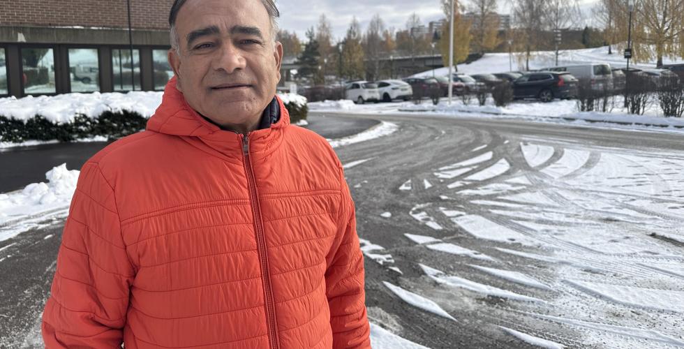 Ombir Singh Upadhyay st&aring;r i en oransje jakke utenfor et bygg p&aring; Stovner i Oslo. 