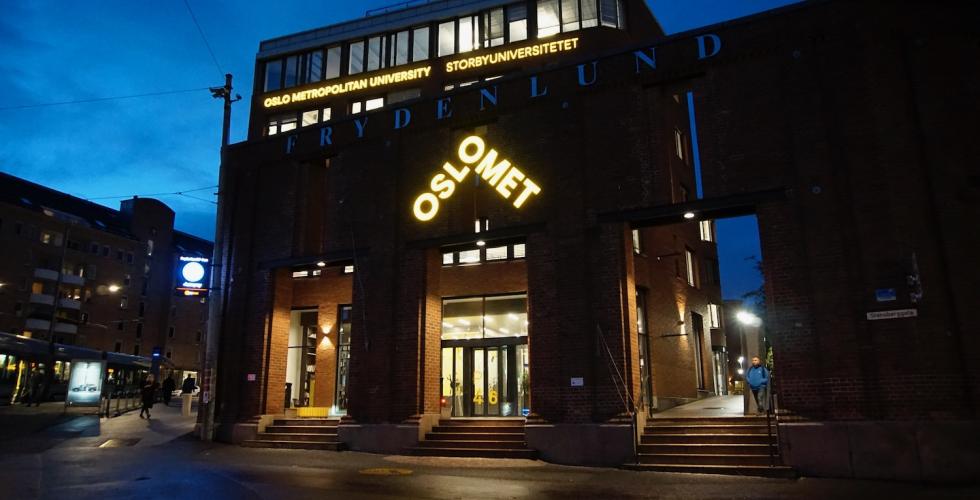 Bilde av OsloMet med skolens logo i sterkt fokus da det er m&oslash;rkt ute. 