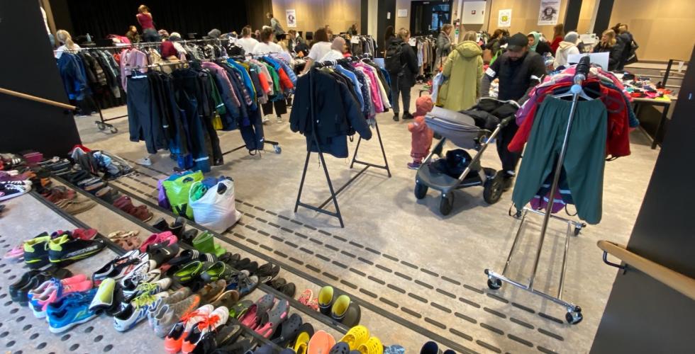 oversiktsbilde av klesbyttemarked med kl&aelig;r, sko og mennesker som titter