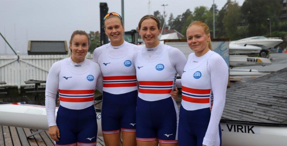 De fire padlerne er if&oslash;rt norgesdrakter og smiler ved siden av hverandre