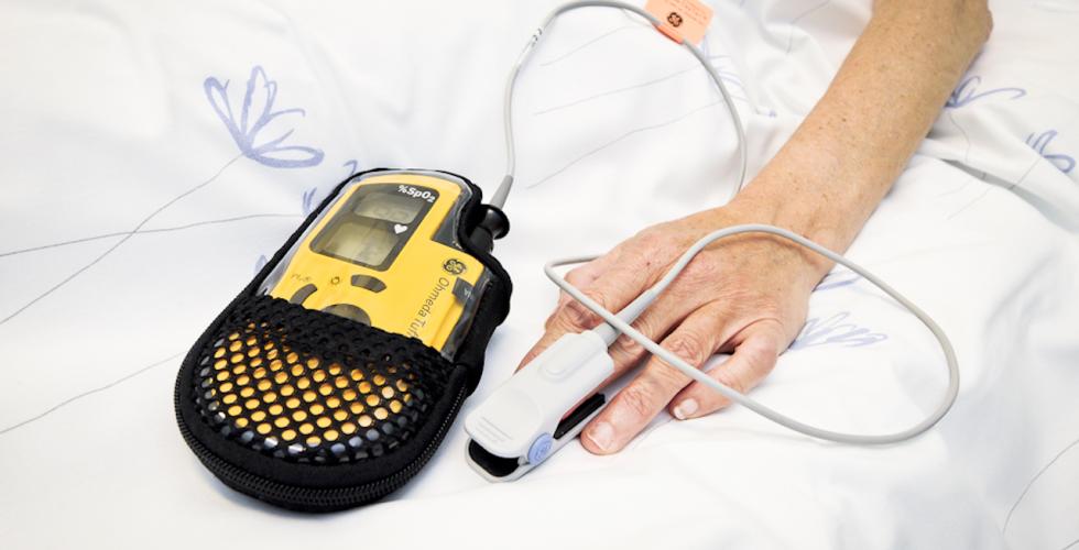 En pasient har h&aring;nden sin p&aring; sykesengen. 