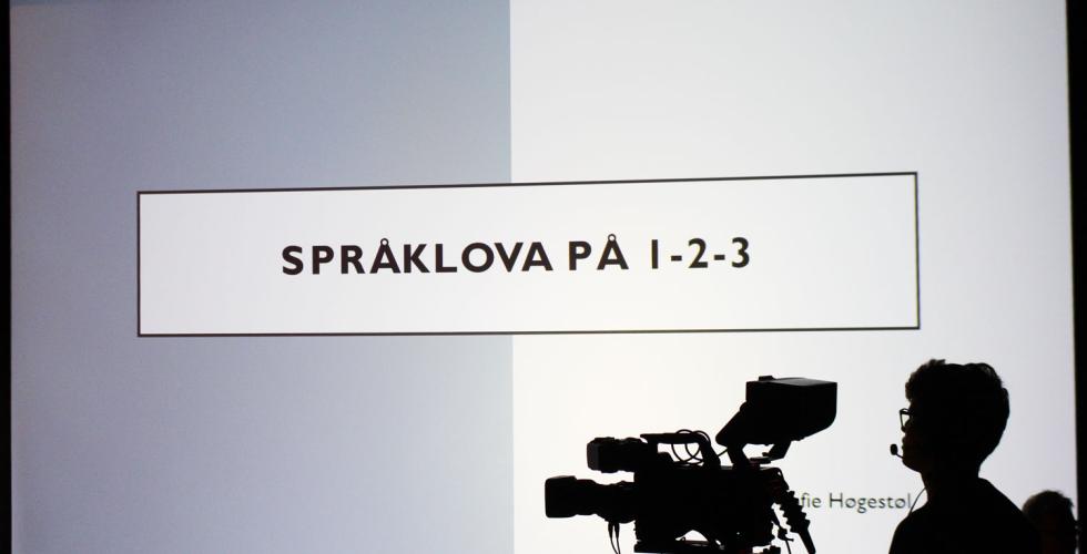 Bilete av framf&oslash;ringa p&aring; Spr&aring;kdagen. Kameramann i siluett p&aring; h&oslash;gre side. 