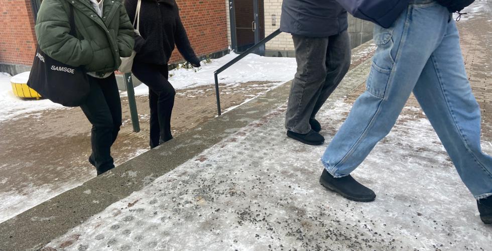 Studenter som g&aring;r over en is- og grusbelagt vei.
