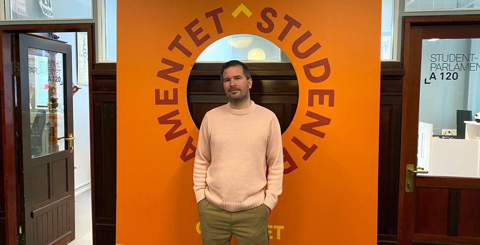 Lederen for Studentparlamentet ved OsloMet st&aring;r foran plakat